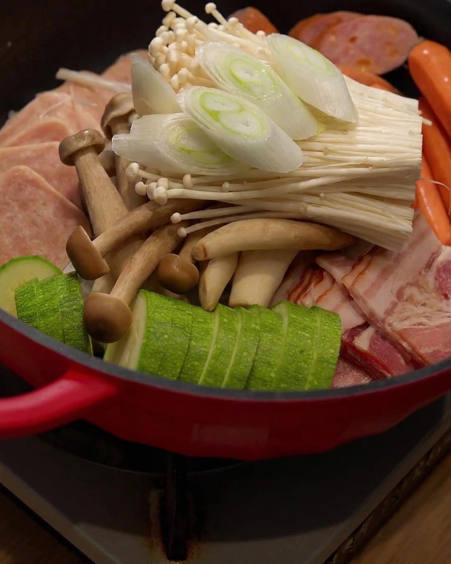 Trozos de cebolla verde recién cortados siendo colocados encima de los ingredientes dentro del hot pot.