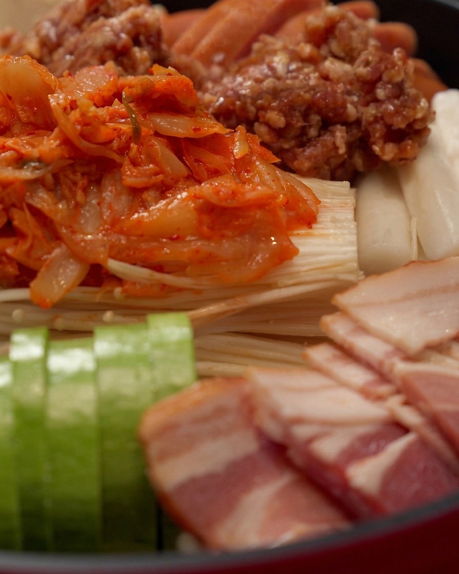 Salsa roja picante para hot pot siendo vertida sobre la parte superior de los ingredientes organizados.