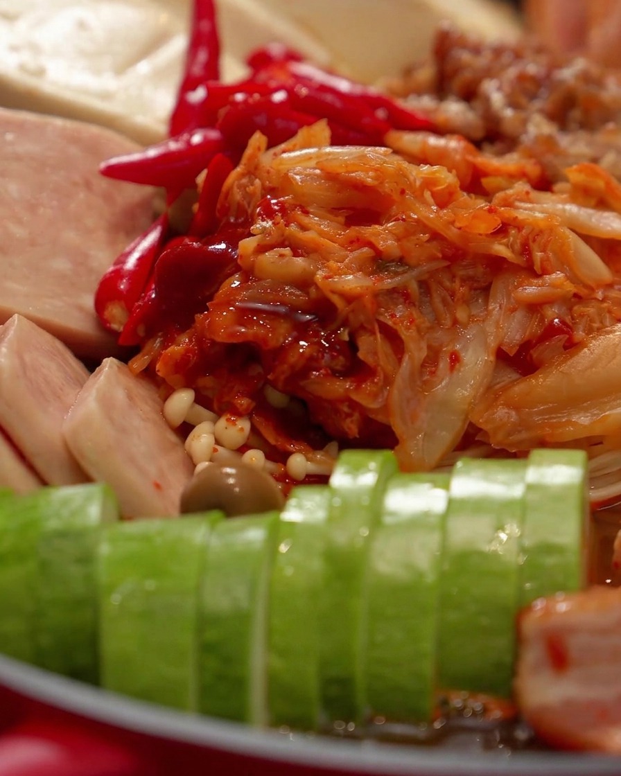 Una vista de cerca de una tapa de cristal cubriendo los ingredientes dentro de la olla roja.