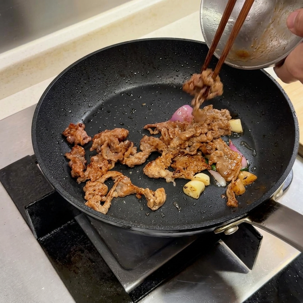 Rodajas de ternera y aromáticos en una sartén con un trozo de mantequilla siendo añadido.