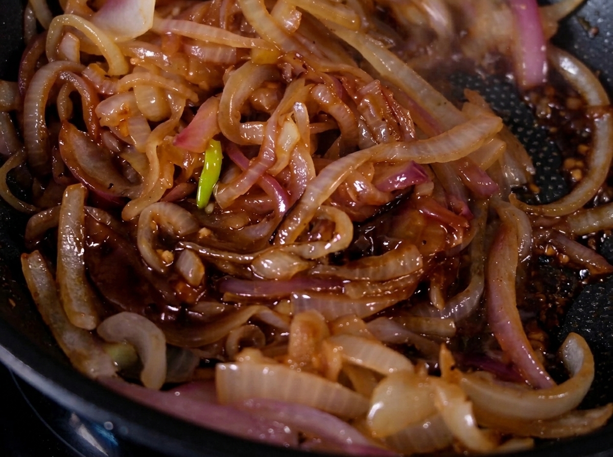 Cebollas caramelizadas brillando con un glaseado dentro de una sartén.
