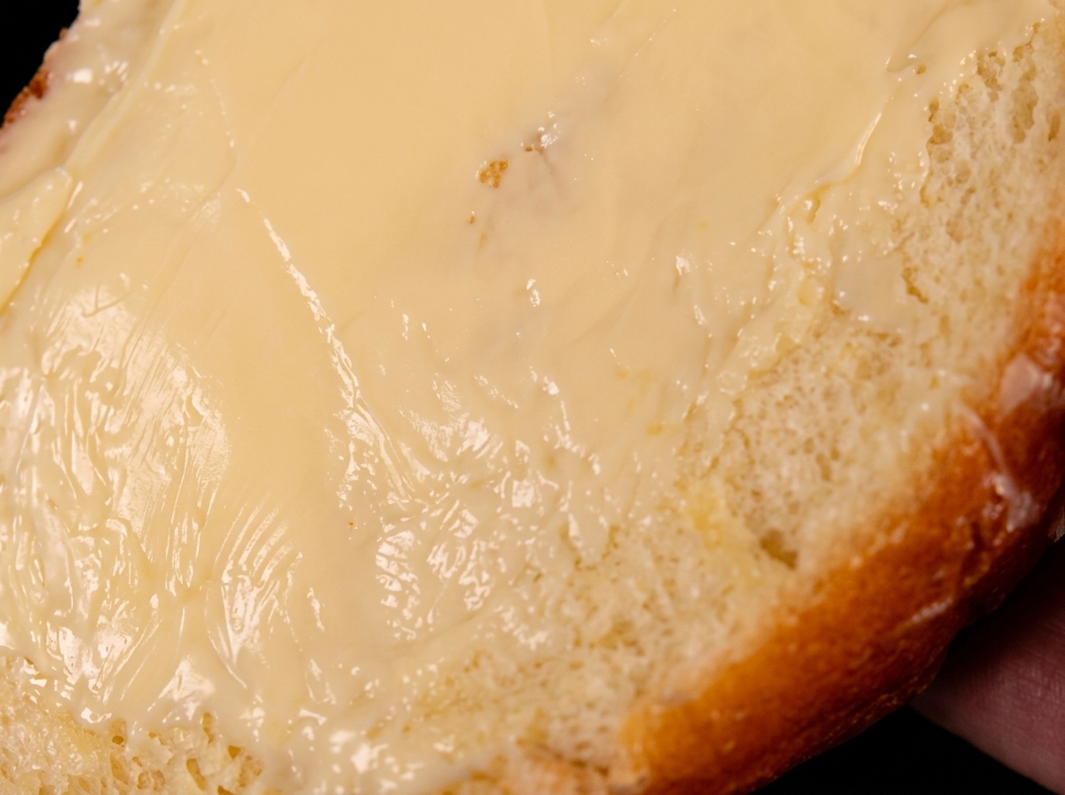 Una sola rebanada de pan cubierta de mantequilla, con la mantequilla hacia abajo en una sartén caliente.