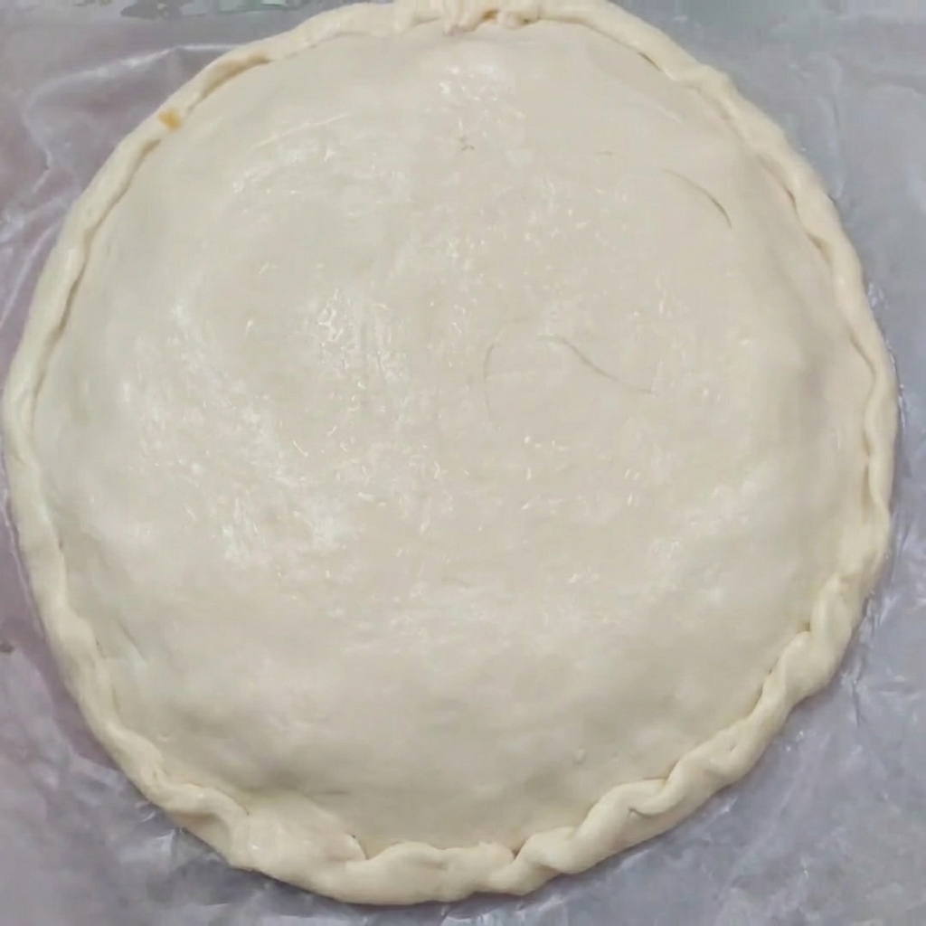 Primer plano de un pastel crudo con bordes bellamente rizados que sellan las masas superior e inferior juntas.