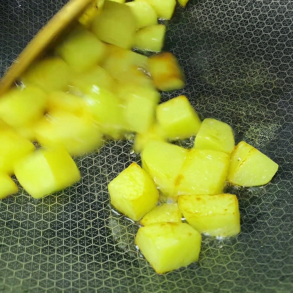 Cubos de patata friéndose en aceite dentro de un wok hasta dorarse.