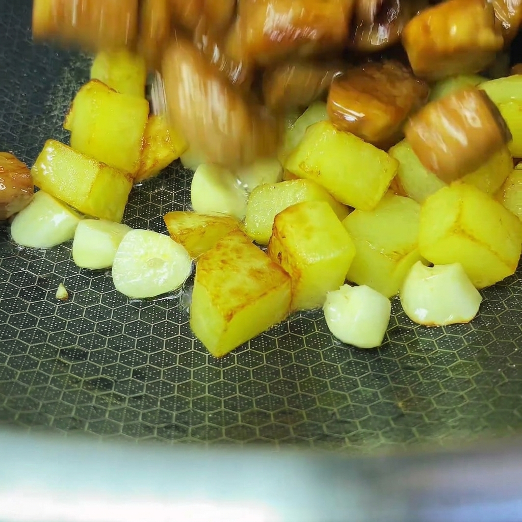 Patatas y cerdo cocinados siendo combinados juntos en un wok.