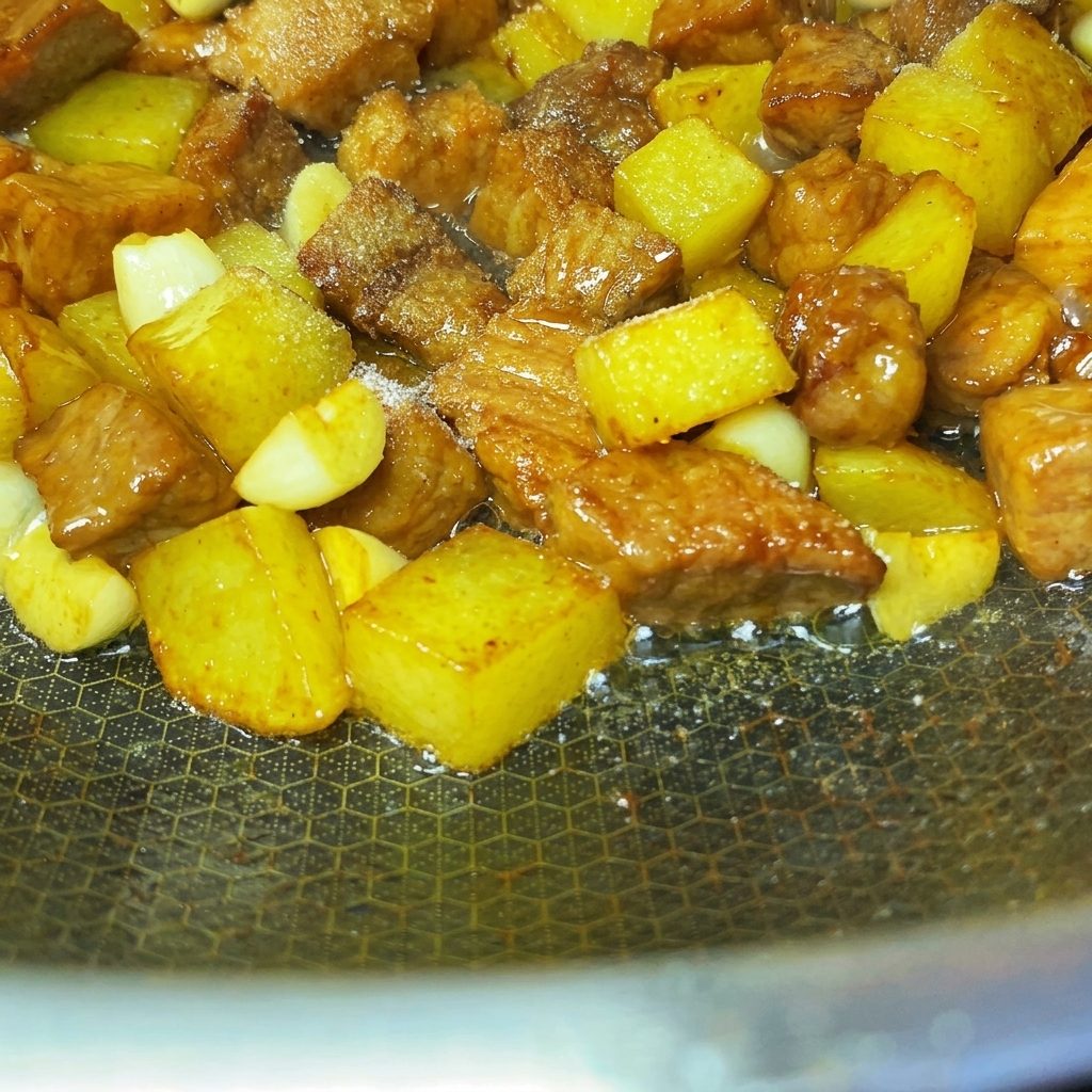 Especias y semillas de sésamo espolvoreadas uniformemente sobre los cubos de cerdo y patata fritos.