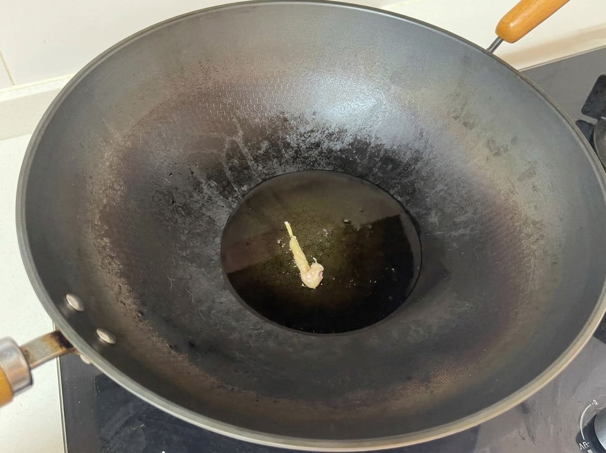 Un solo trozo de pollo rebozado friéndose en el centro de un wok grande con aceite caliente.