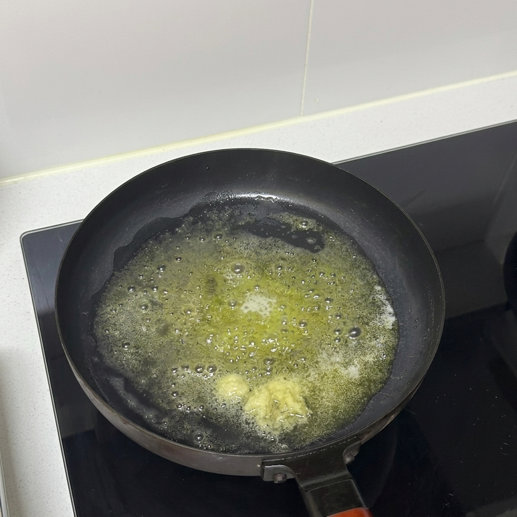 Ajo picado cociéndose en mantequilla derretida dentro de una sartén.