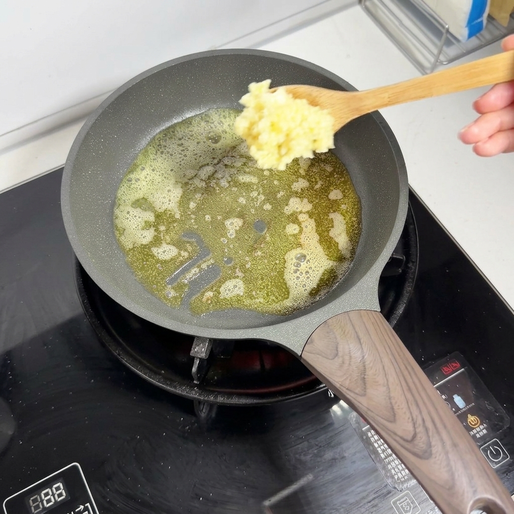 Una cuchara de madera añadiendo ajo picado a la mantequilla derretida que hace espuma en una sartén.