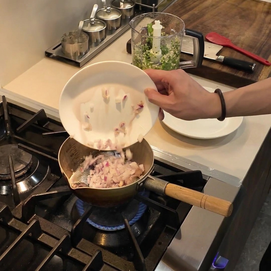 Cebollas rojas picadas deslizándose desde un plato blanco hacia una olla con aceite caliente en la estufa.