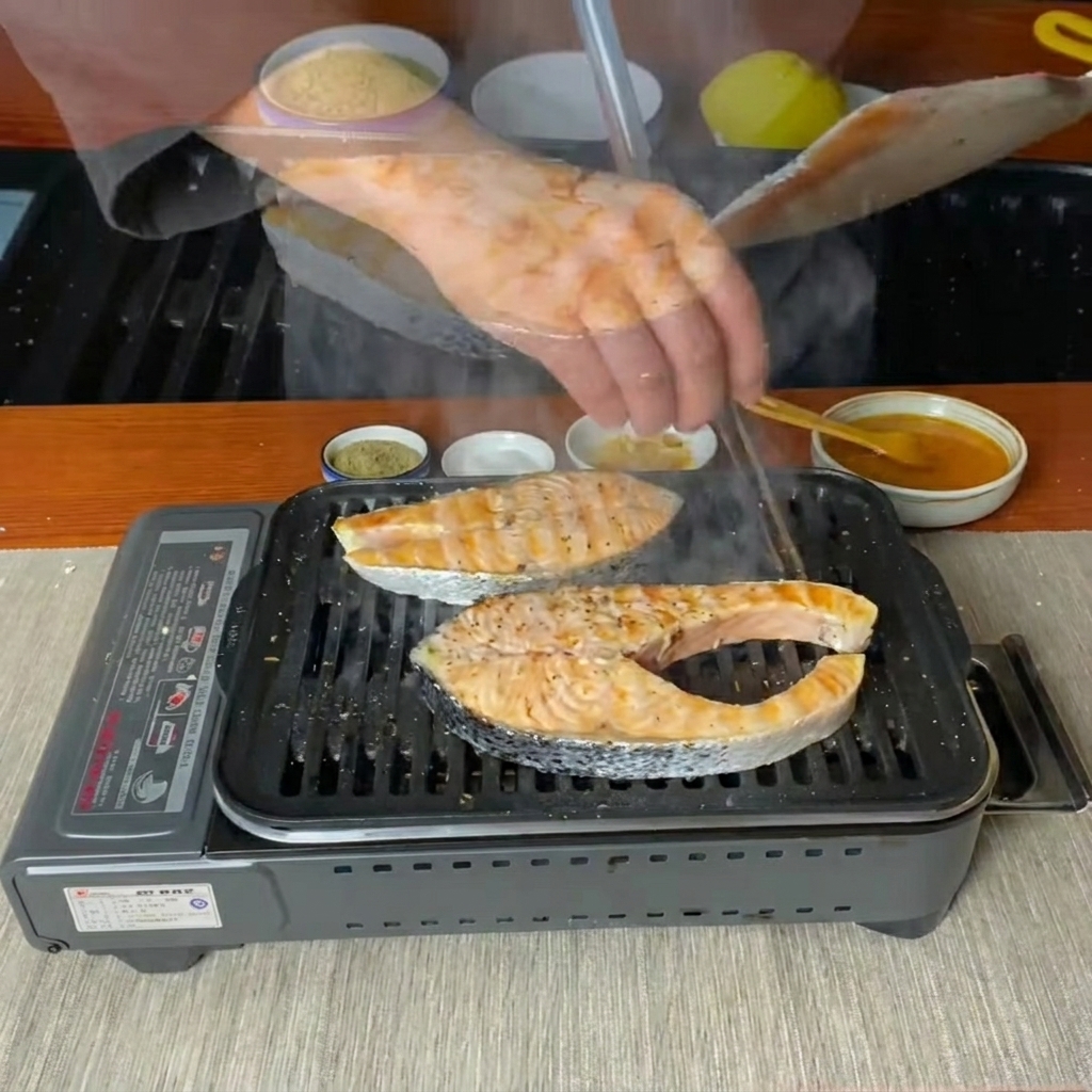 Filetes de salmón siendo volteados con una espátula en una sartén grill caliente.