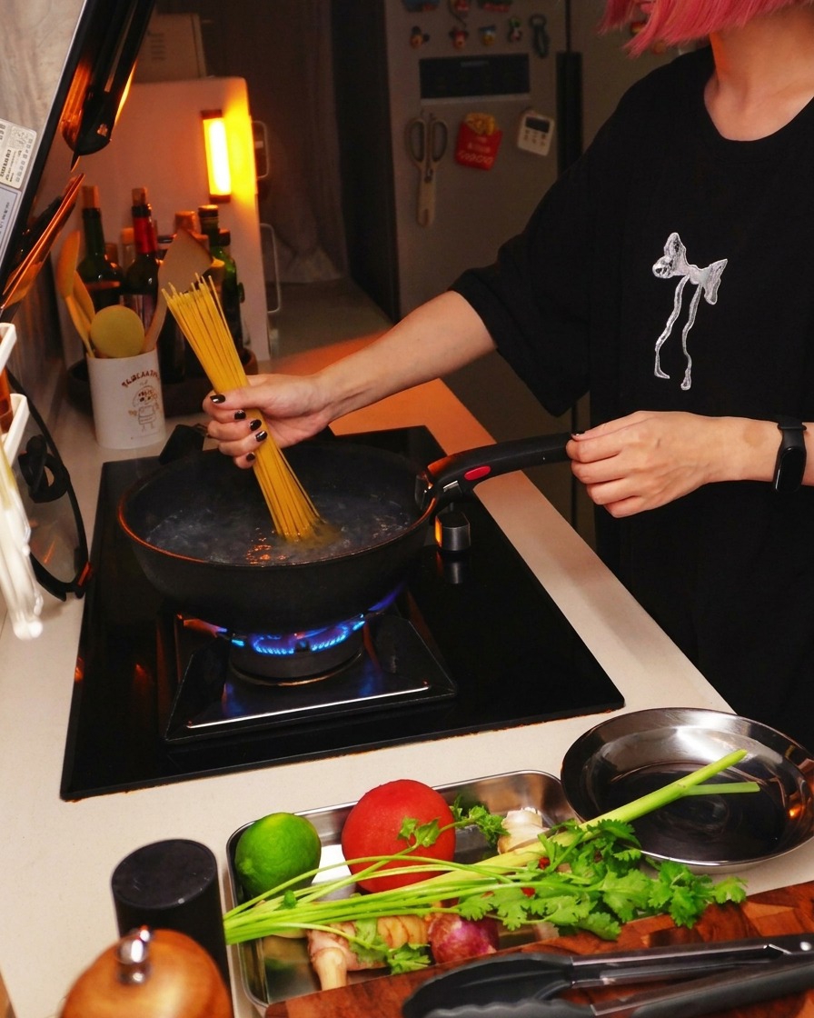 Pasta de espaguetis seca hundiéndose en una olla de agua hirviendo sobre la cocina.