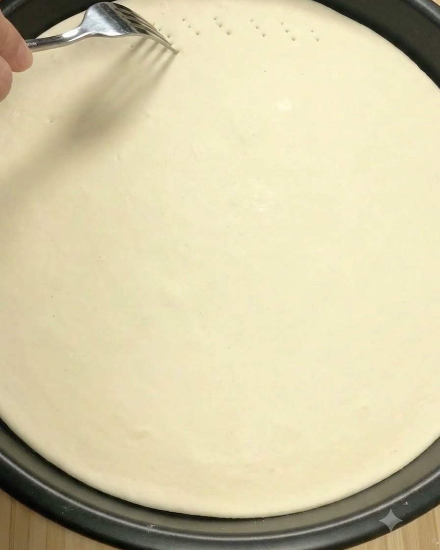 Un tenedor de metal pinchando pequeños agujeros de ventilación en la superficie de la masa de pizza cruda.