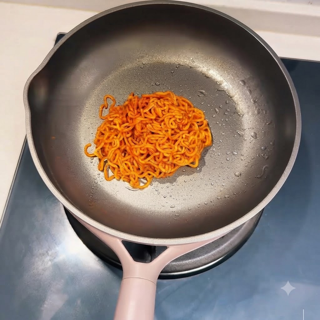 Una porción de fideos rojos picantes cocidos y esparcidos ordenadamente en una sartén.