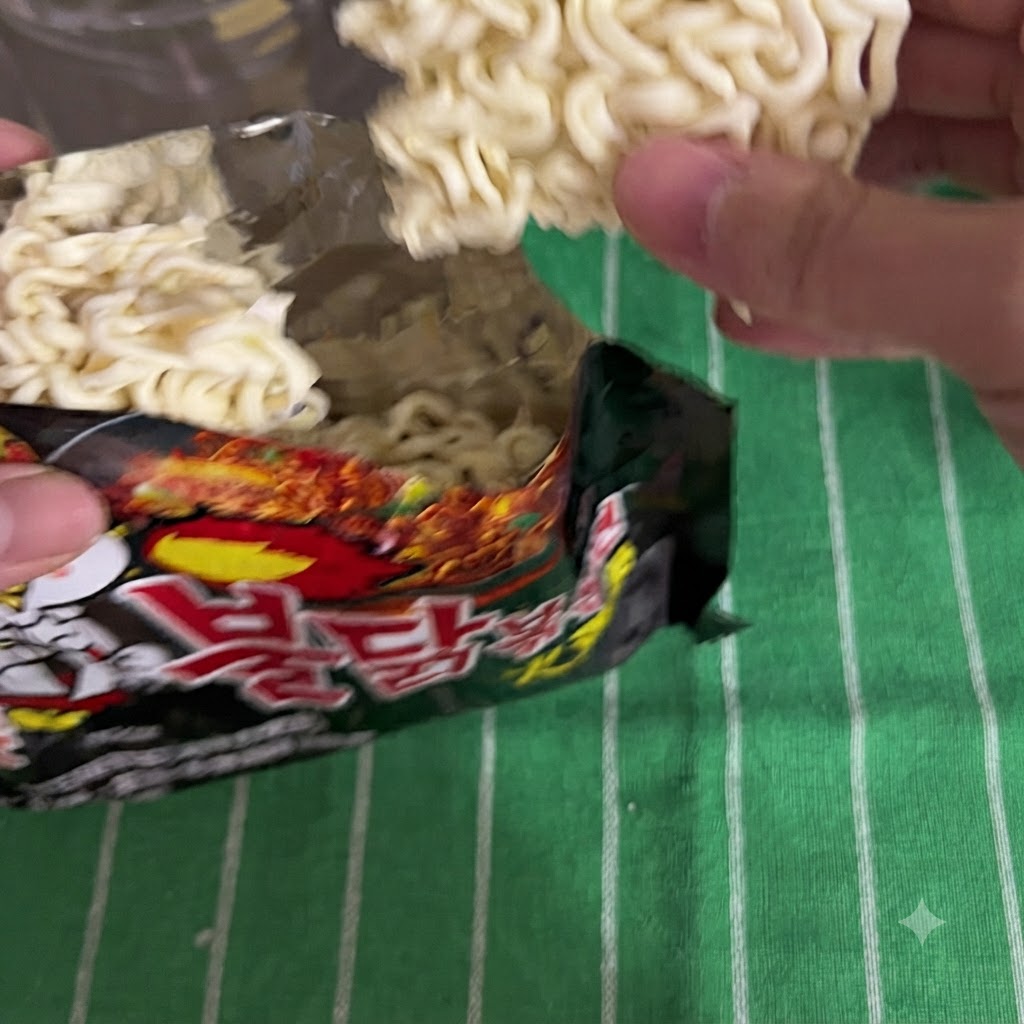 Fideos instantáneos siendo sacados de una bolsa de empaque negra.