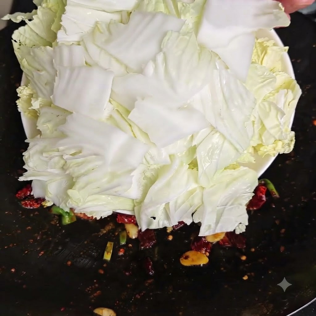 Trozos de repollo chino crudo recién picado siendo volcados desde un plato blanco hacia un wok caliente.