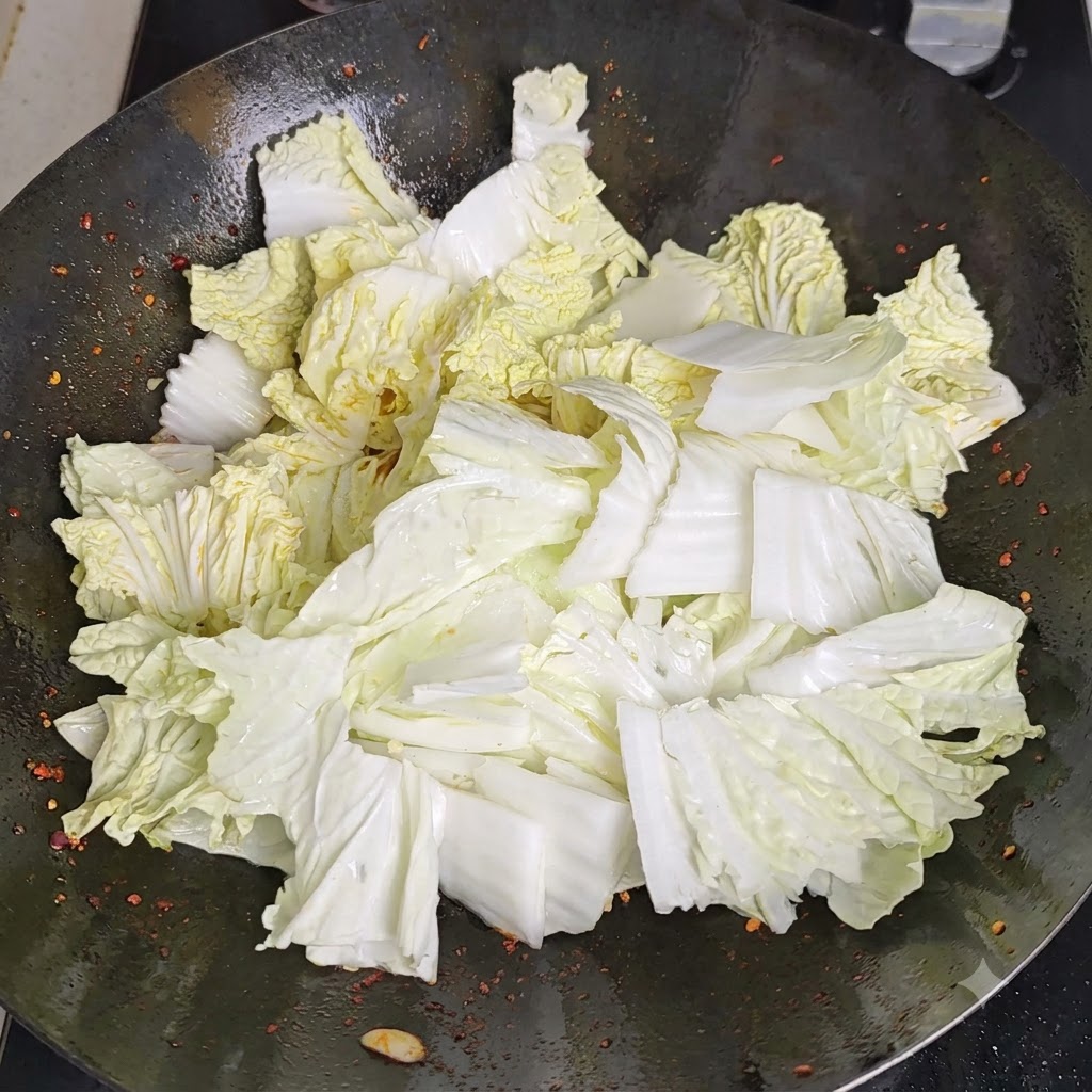 Vinagre siendo vertido a lo largo del perímetro calentado del wok, reaccionando con la superficie caliente.