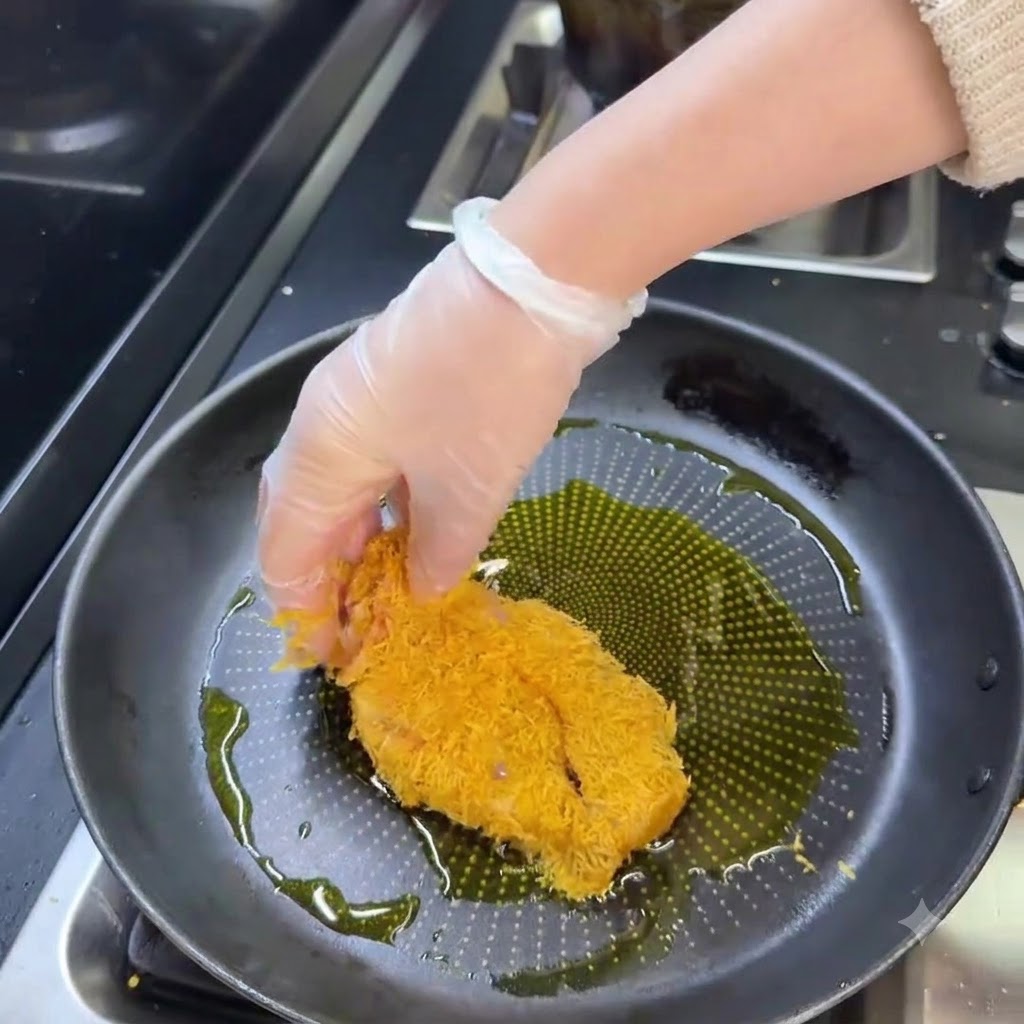 Una milanesa de cerdo empanizada friéndose en una sartén con aceite caliente hasta dorarse.