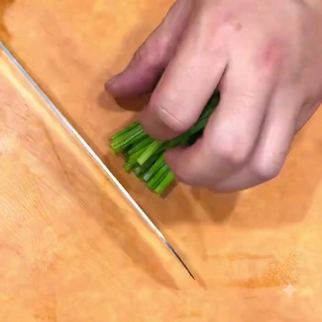 Cebollas verdes siendo picadas en forma de flor de cebollino sobre una tabla de madera con un cuchillo.