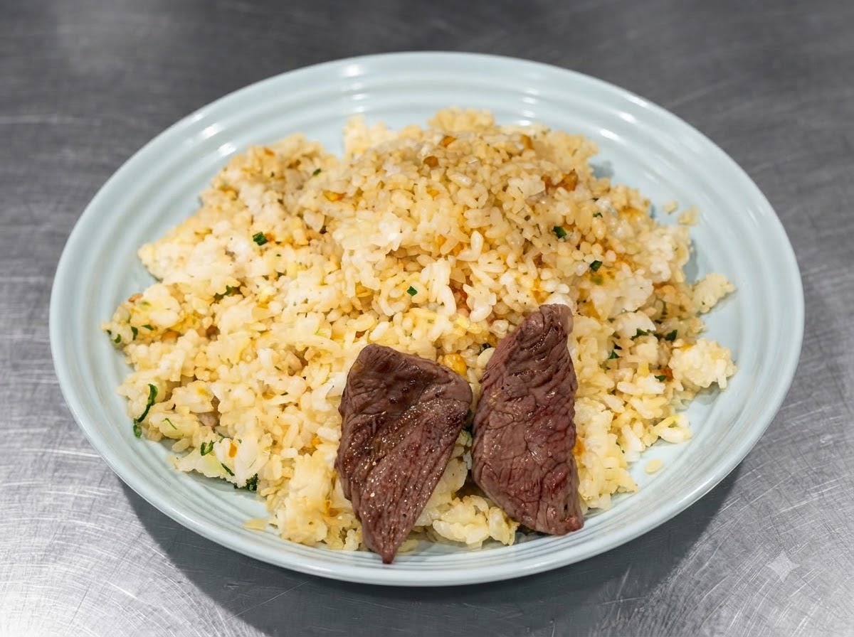 Trozos de bistec sellado siendo organizados encima del arroz sazonado en un plato azul usando pinzas.