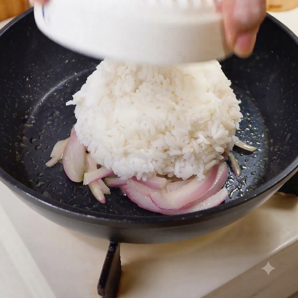 Una cúpula moldeada de arroz blanco volcada en el centro de una sartén con cebollas.