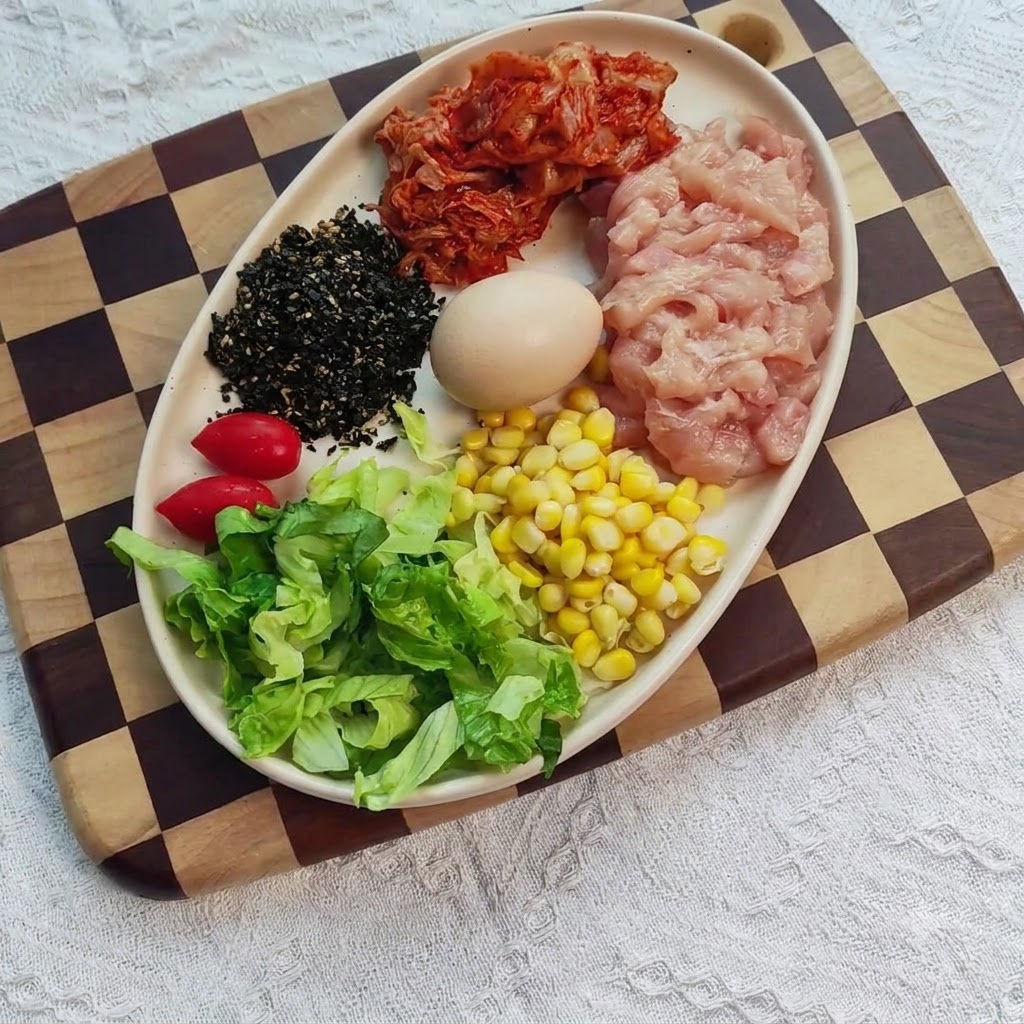 Pechuga de pollo en dados en un bol mezclada con condimentos, jengibre y ajo.
