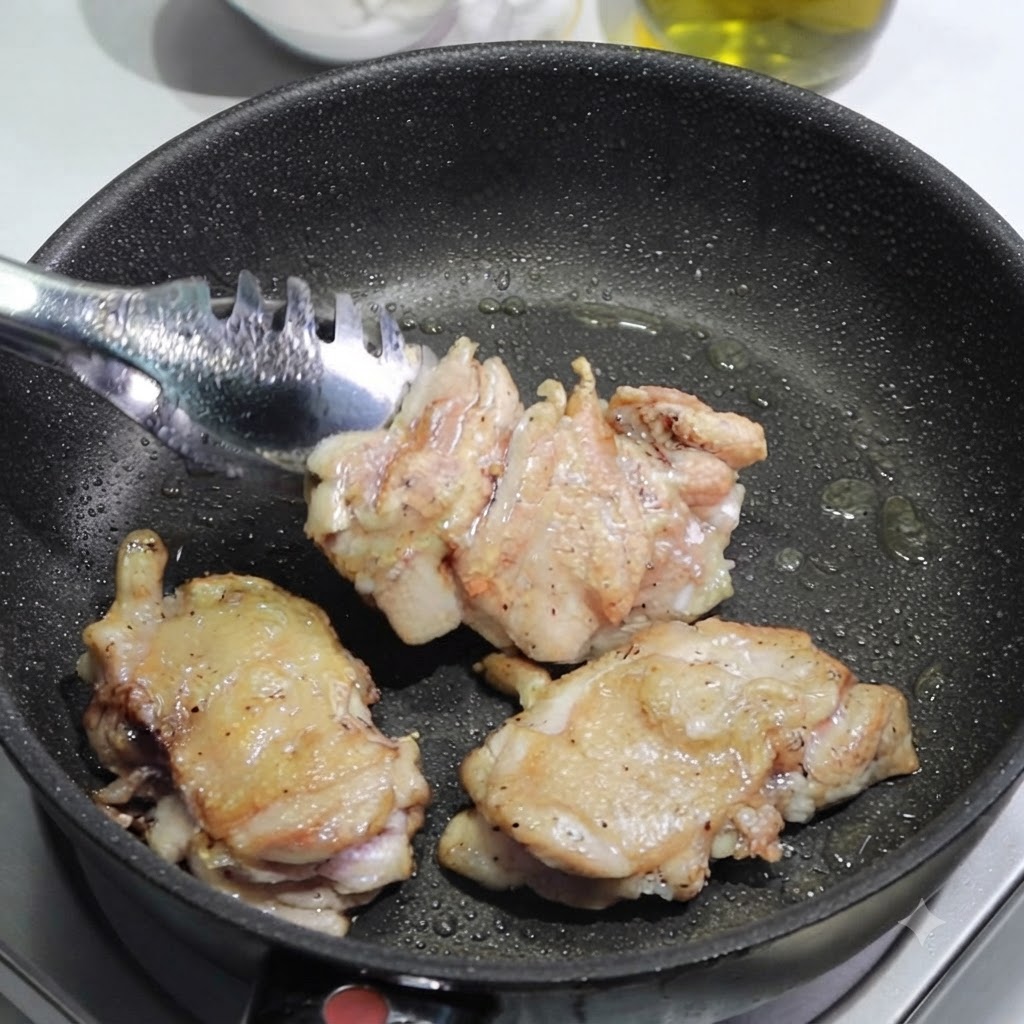 Pinzas colocando muslos de pollo dorados fuera de una sartén sobre una tabla de cortar para ser cortados.