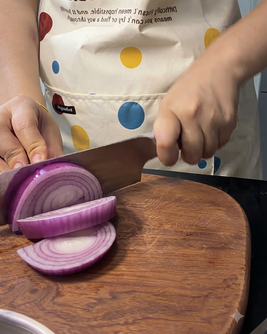 Una cebolla morada siendo rebanada en una tabla de madera con un cuchillo.