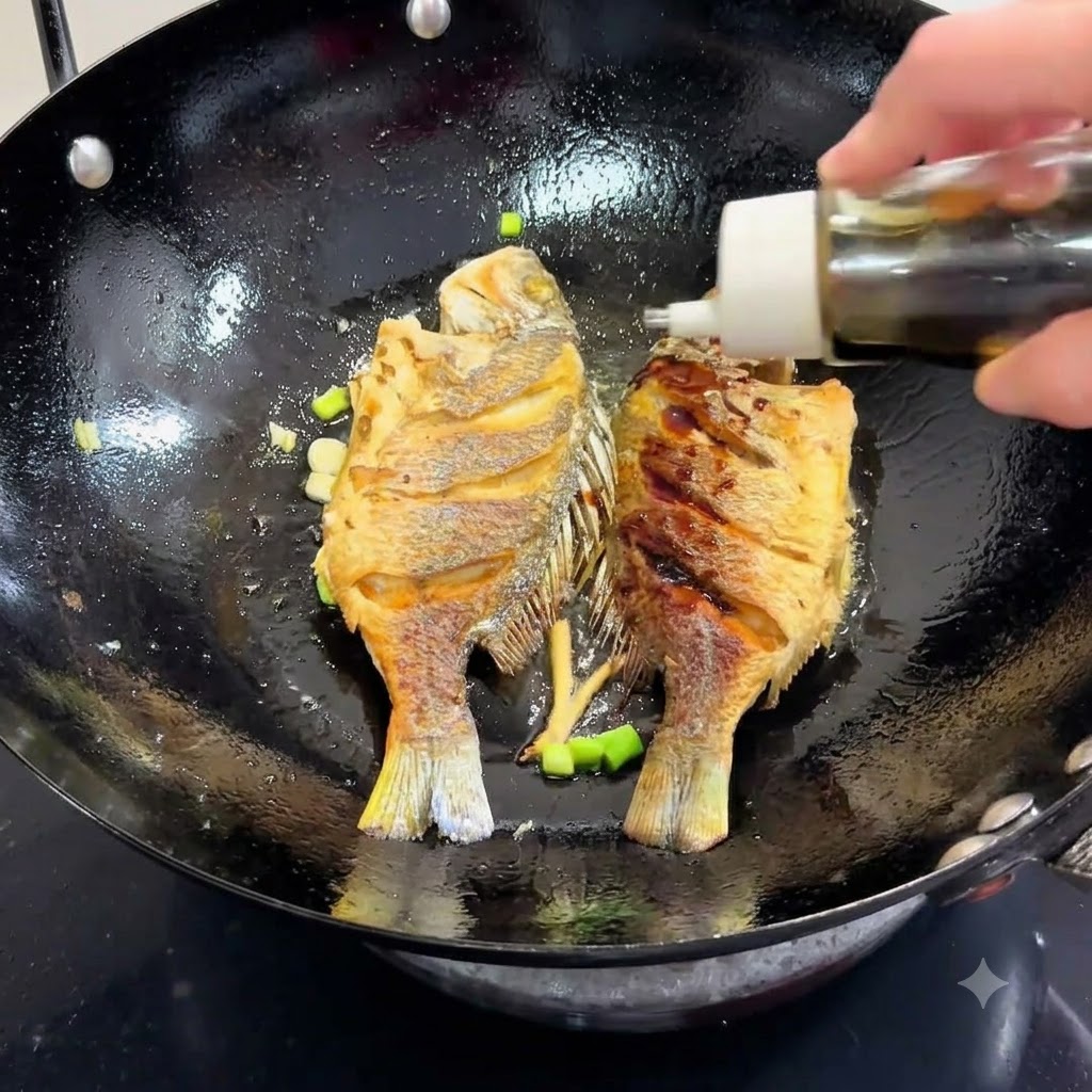 Salsa de soja siendo vertida desde una botella en un wok que contiene pescado frito y cebollinos.