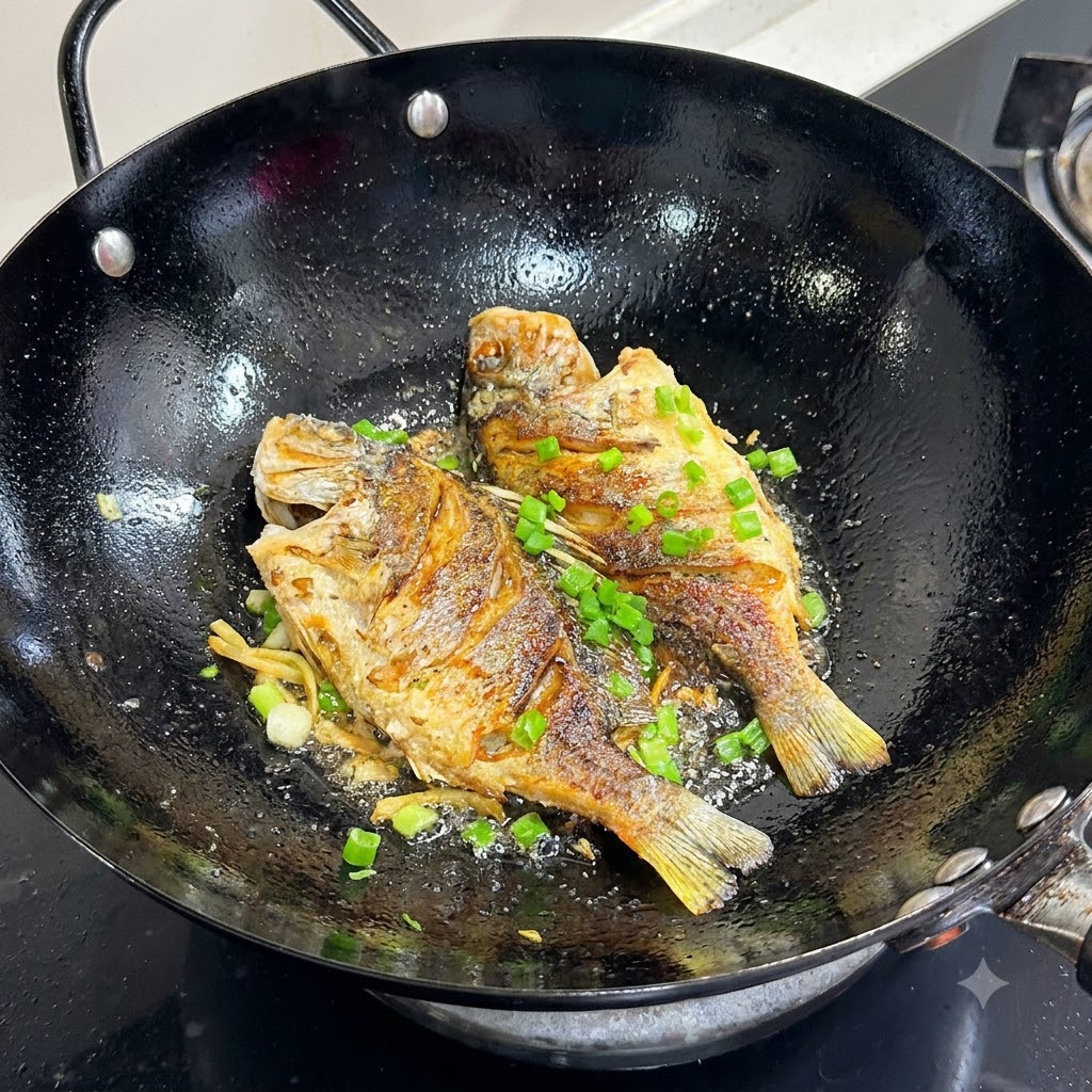 Cebollinos picados siendo espolvoreados encima de un pescado frito dorado en un wok negro.