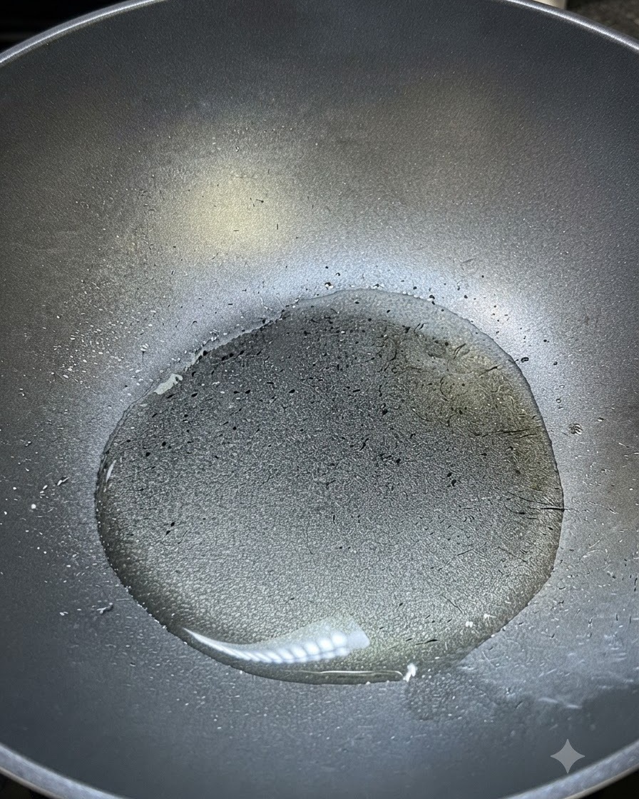 Aceite de cocina caliente brillando dentro de un wok oscuro listo para sazonar.