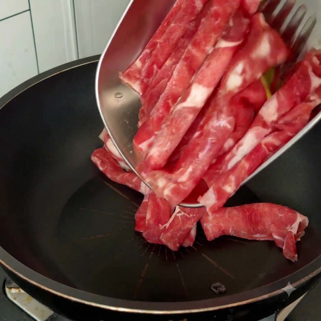 Tiras de carne cruda siendo vertidas en una sartén negra desde una bandeja metálica con utensilios de cocina.