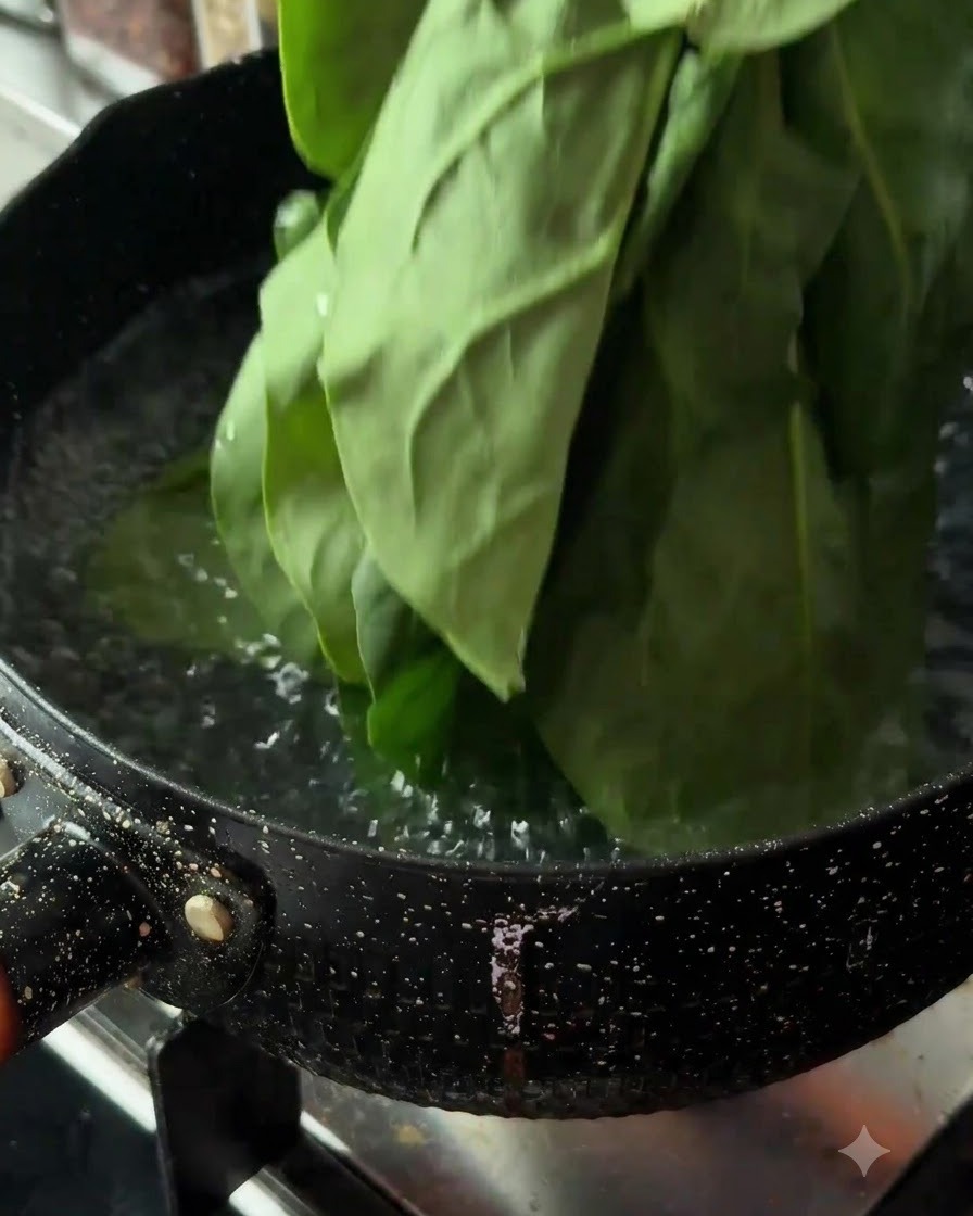 Hojas de espinaca fresca siendo sumergidas en una olla con agua hirviendo en la estufa.