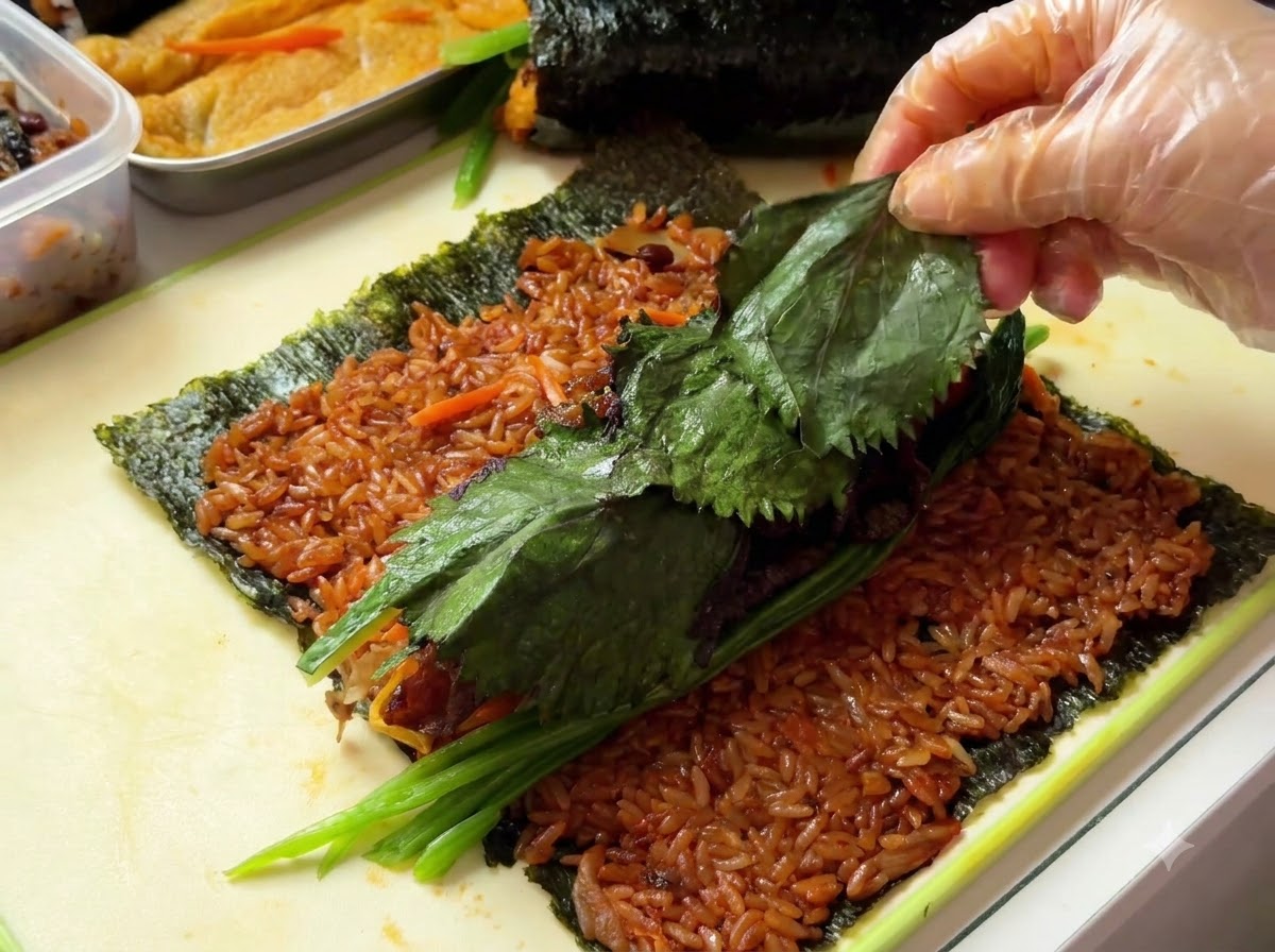 Hojas de perilla siendo colocadas sobre la parte superior de los ingredientes del relleno.