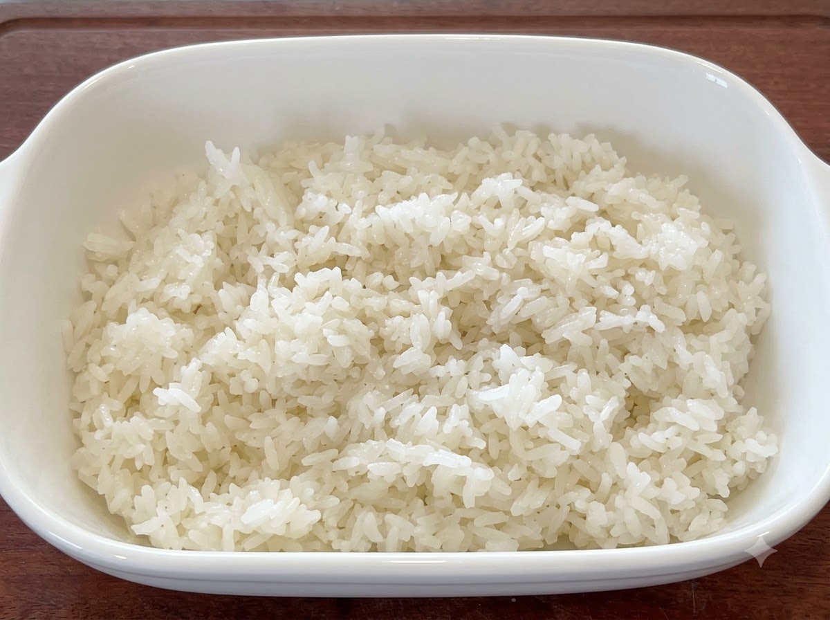 Arroz blanco fresco mezclado con semillas de sésamo y aceite en un plato de servicio blanco.