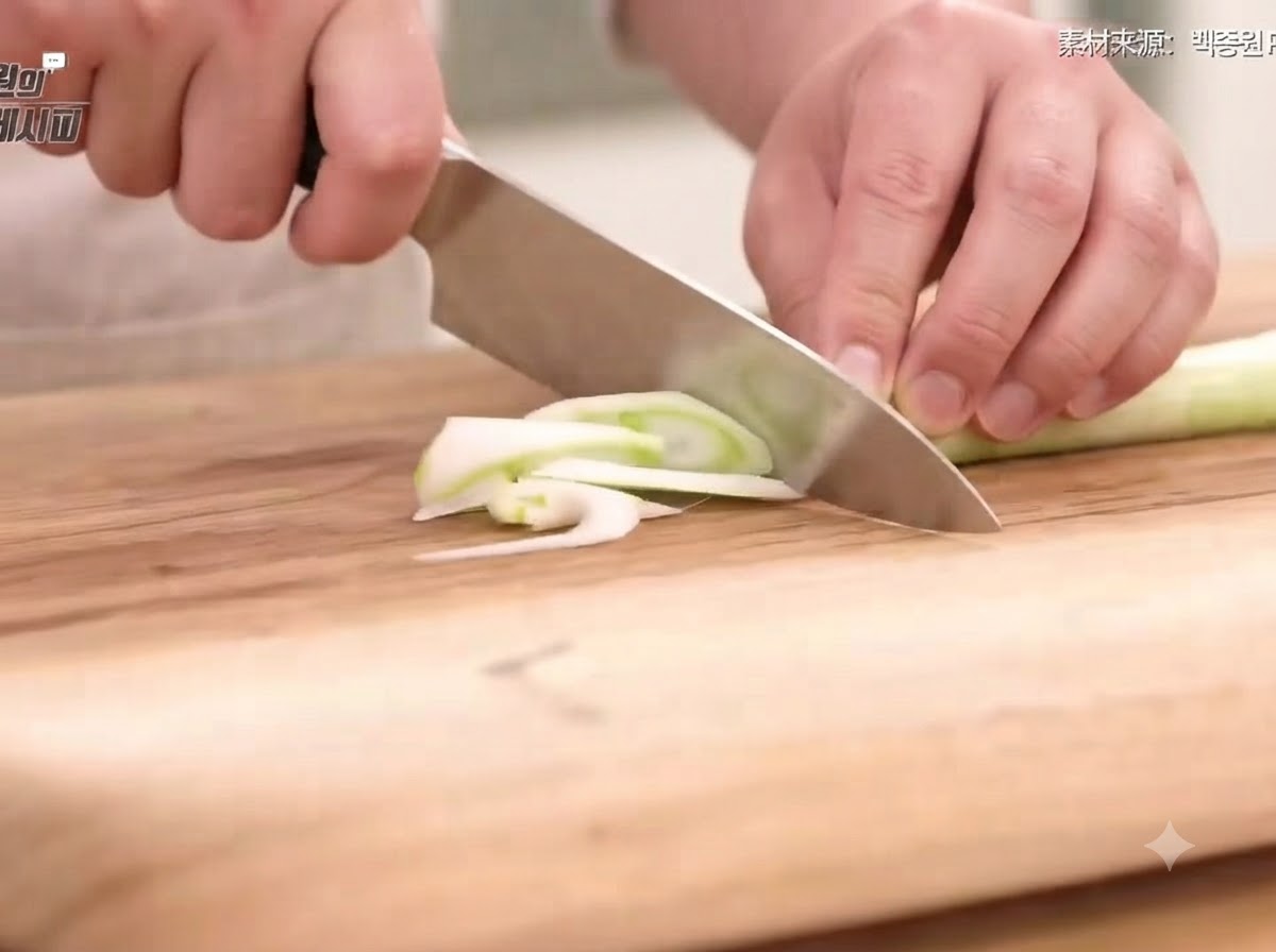 Cebolla verde, cebolla, zanahoria y chiles cortados en rodajas finas y tiras sobre una tabla de cortar de madera con un cuchillo.