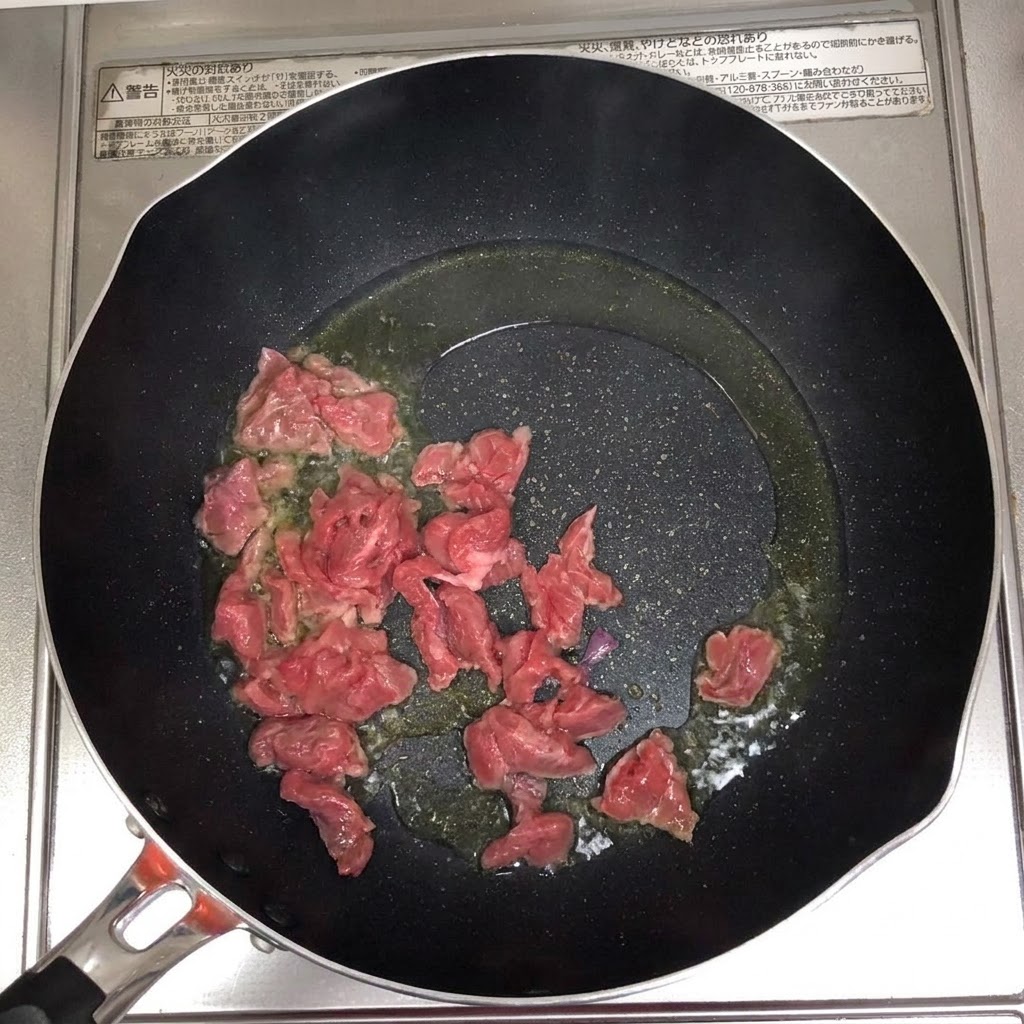 Trozos de ternera chisporroteando y dorándose en una sartén caliente con aceite.