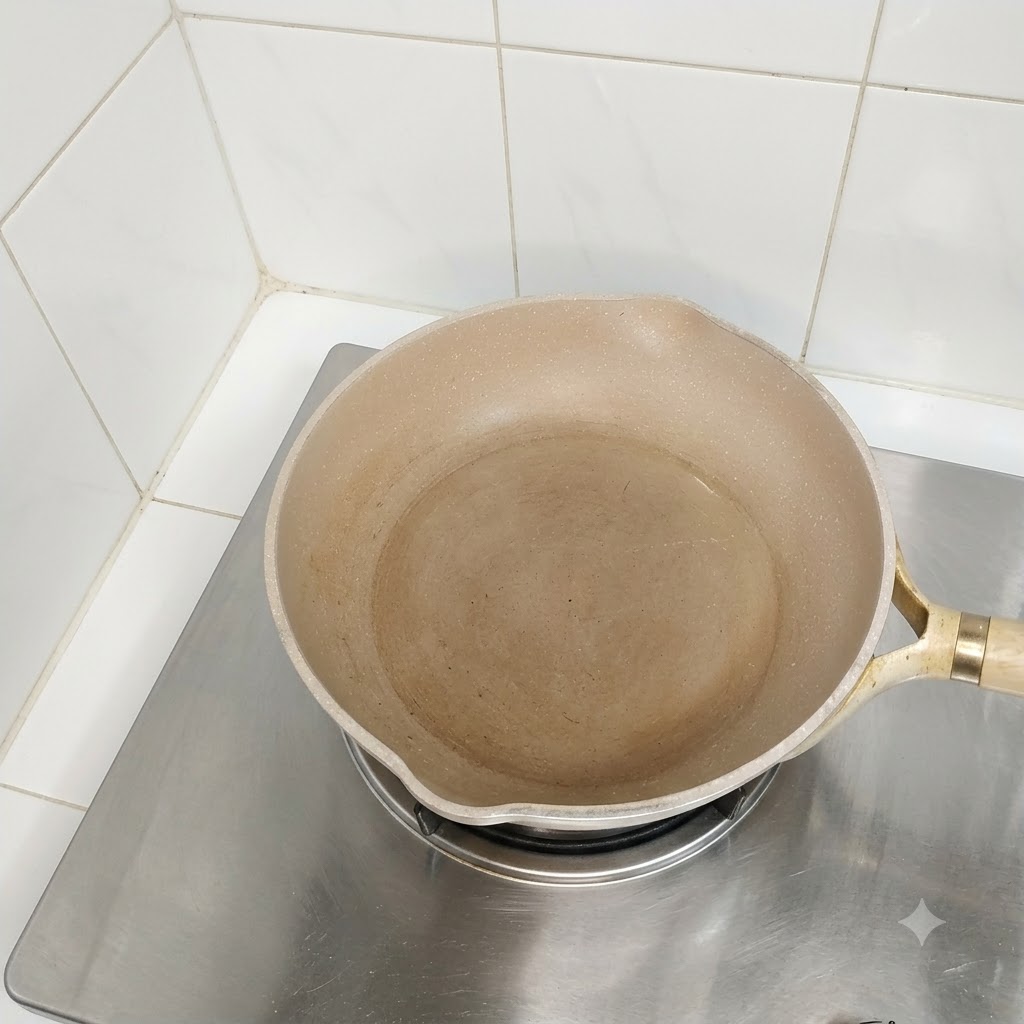 Una sartén aceitada vacía sobre la hornalla de una estufa lista para cocinar.