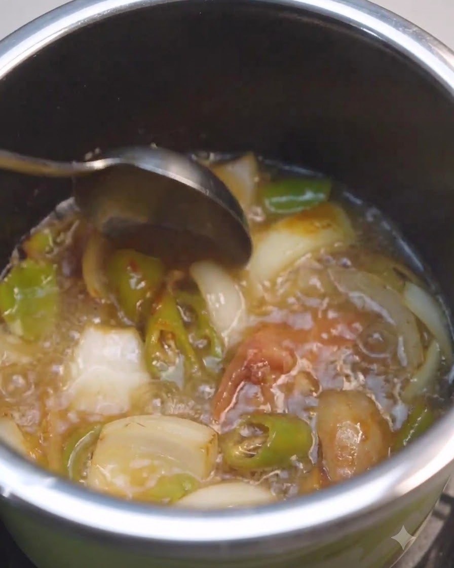 Una cuchara removiendo líquido y pasta de soja dentro de una olla con verduras.