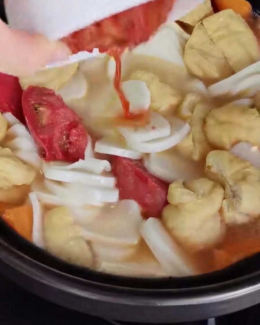 Kimchi picado siendo vertido y mezclado en el caldo de la sopa.