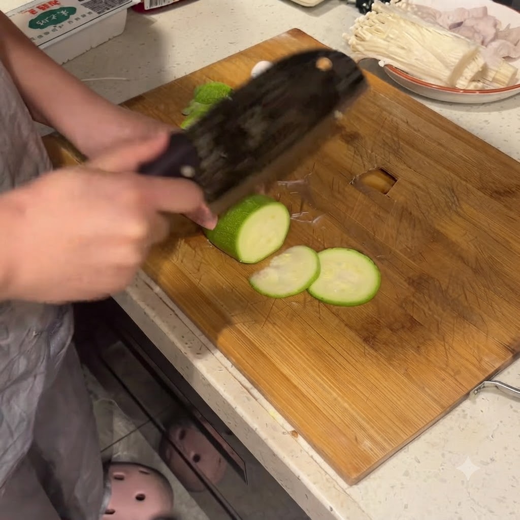 Calabacín cortado en rodajas limpias sobre una tabla de cortar de madera con un cuchillo grande.