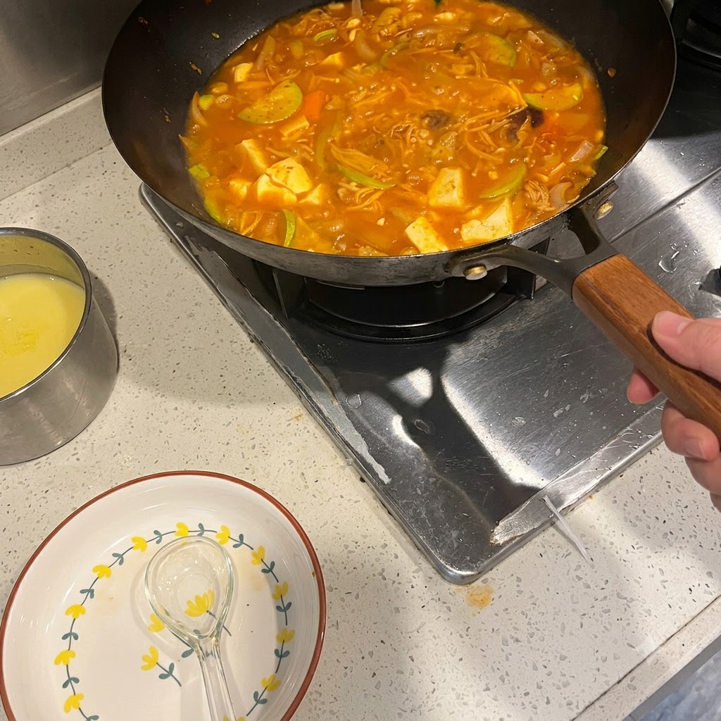 Pasta de ají coreano siendo mezclada en una olla humeante de sopa picante con verduras y carne.