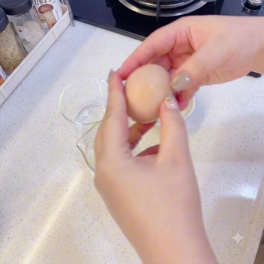Manos separando cuidadosamente una yema de la clara de huevo sobre recipientes de vidrio transparente.