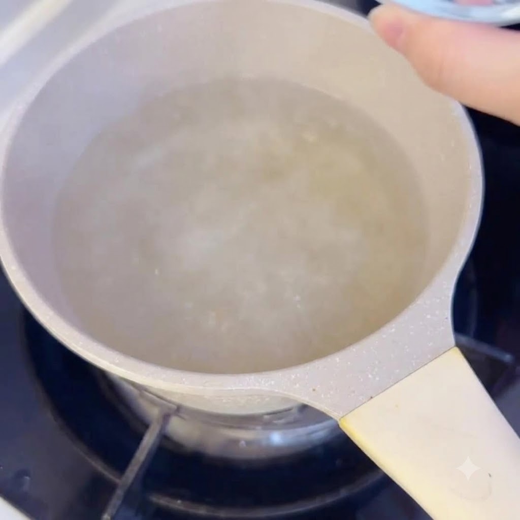 Pasteles de arroz en rodajas echados en una olla con caldo hirviendo en la estufa.
