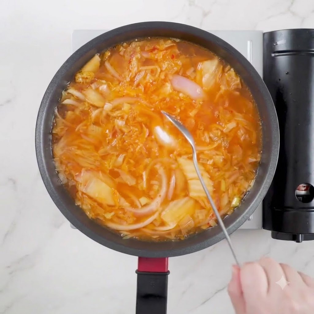 Una cuchara de salsa de soja clara siendo vertida en la olla de sopa a fuego lento.