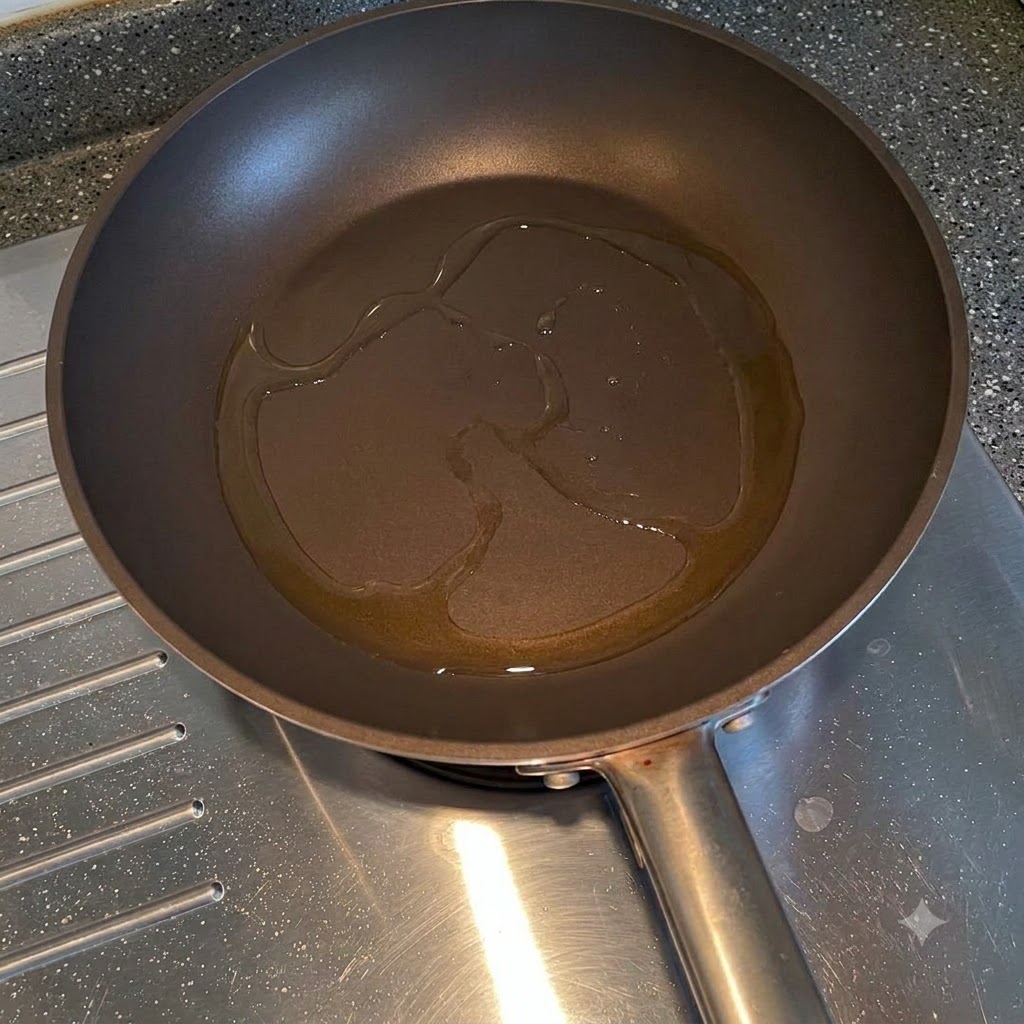 Cebollas amarillas cortadas friéndose en aceite de cocina dentro de una sartén.