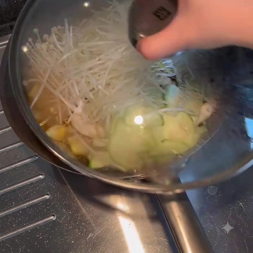 Una tapa de vidrio colocada sobre una sartén llena de verduras hirviendo a fuego lento y caldo.
