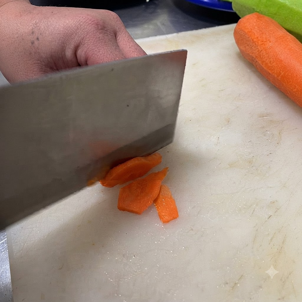 Un cuchillo cortando un chile verde en rodajas sobre una tabla de cortar blanca.