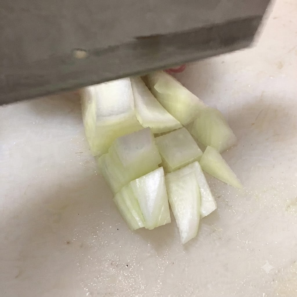 Un cuchillo cortando tofu firme en cubos gruesos sobre una tabla de cortar blanca.