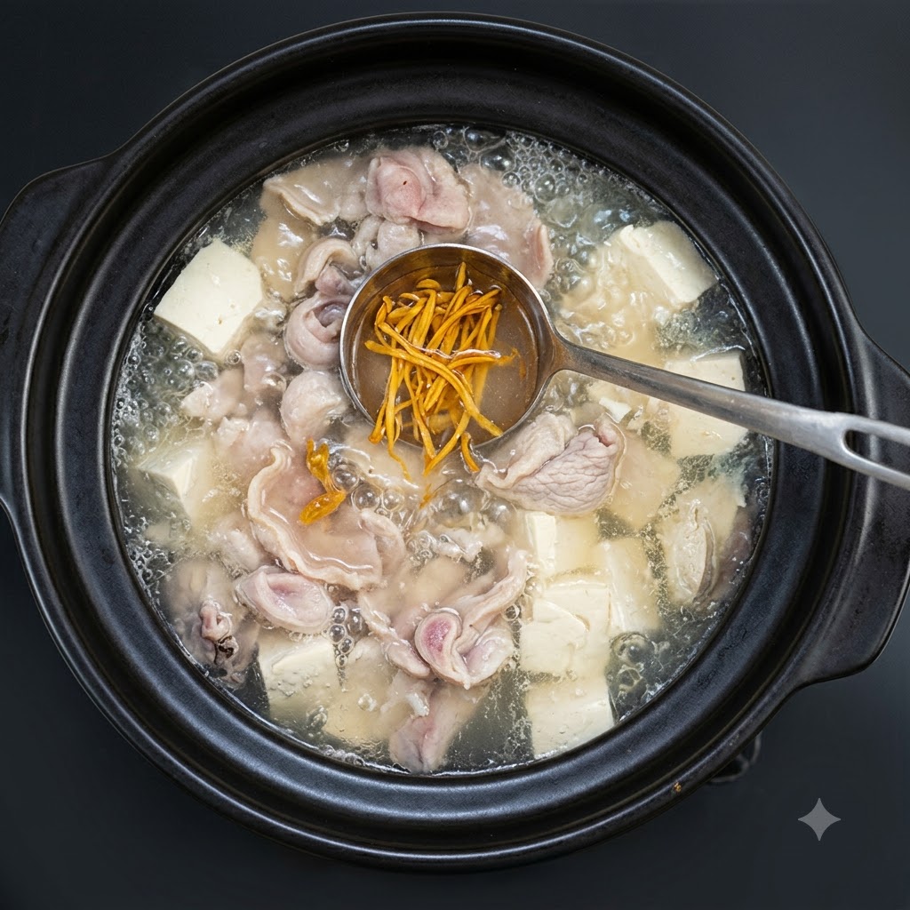 Cebollletas picadas siendo esparcidas sobre la sopa hirviendo en la olla de barro.